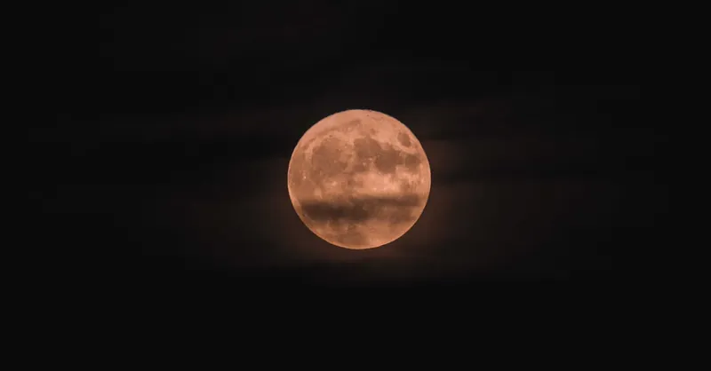 Moon natural satellite of Earth shining over dark sky with clouds at night