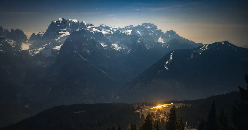 Stunning astrophotography showcasing the Milky Way over snow-capped Italian Alps at night.