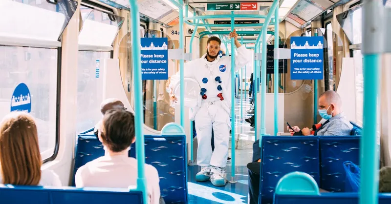 Person in astronaut costume traveling on London public transit, promoting safe distancing.
