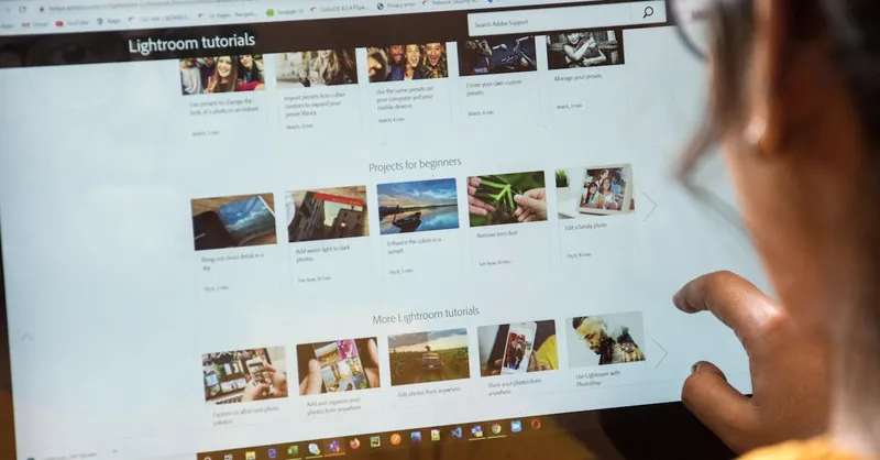 A woman exploring Adobe Lightroom tutorials online for learning and photo editing.