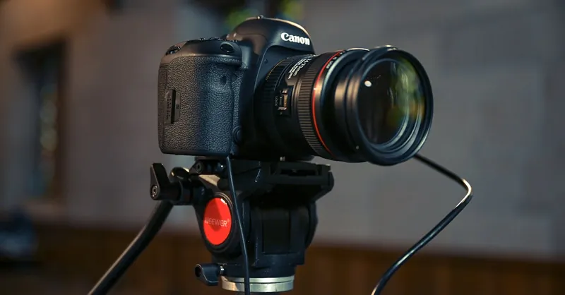 Close-up of a DSLR camera mounted on a tripod in an indoor setting. Perfect for photography themes.