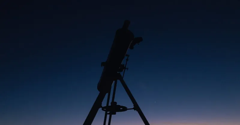 Silhouette of a telescope against a twilight sky, perfect for astronomy enthusiasts.