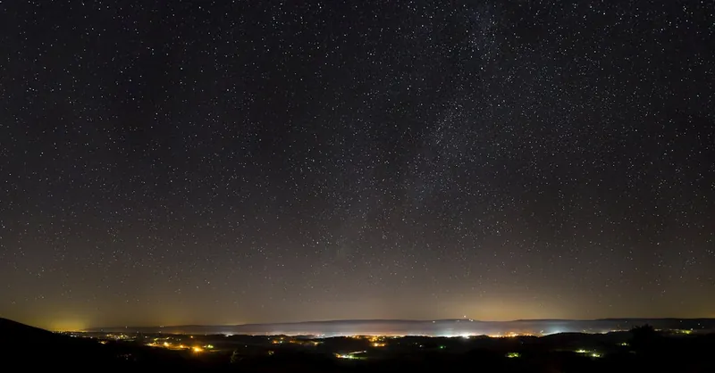 A breathtaking view of a starry night sky over an illuminated urban landscape, perfect for astronomy enthusiasts.