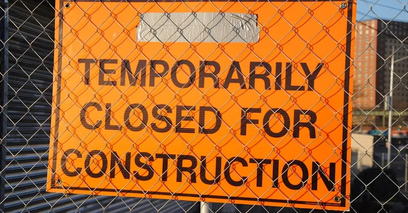 Orange sign behind fence reading