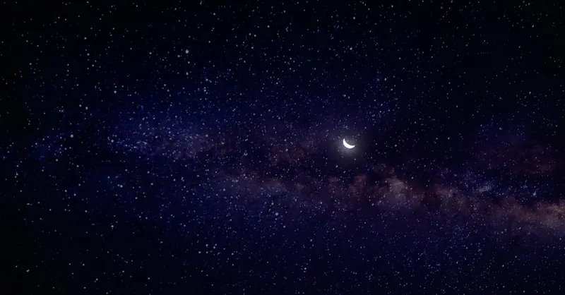 A serene view of a crescent moon nestled in a star-filled night sky with the Milky Way.