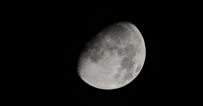Detailed photograph of a crescent moon in the night sky showcasing its craters and textures.