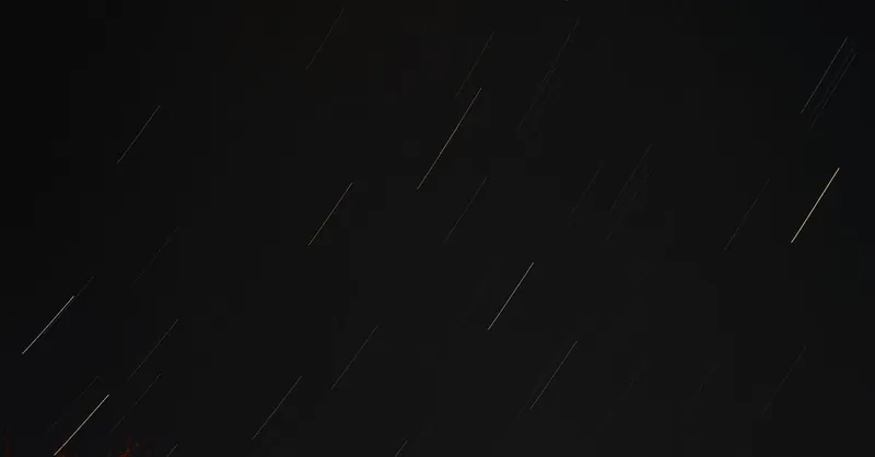 Long exposure shot of star trails and light streaks in the night sky.