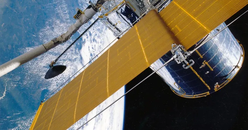 Spacecraft with solar panels orbiting Earth, showcasing modern astronautic technology.