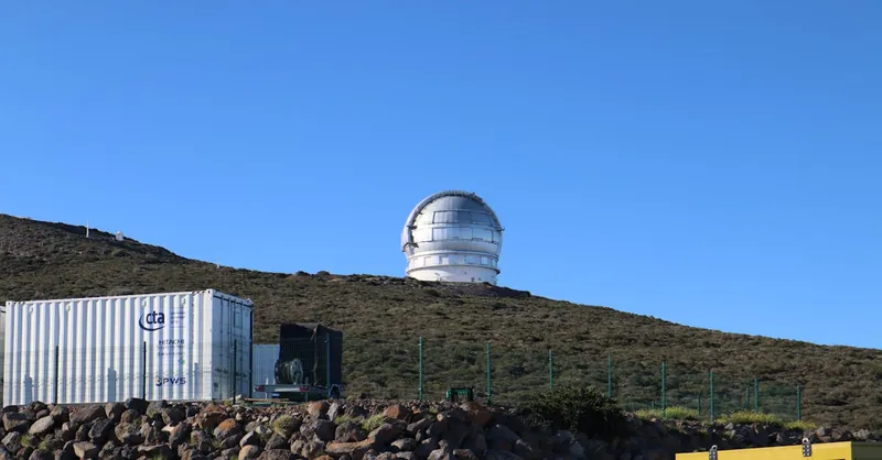 A large observatory dome sits on a hill beneath a clear blue sky, ideal for astronomy enthusiasts.