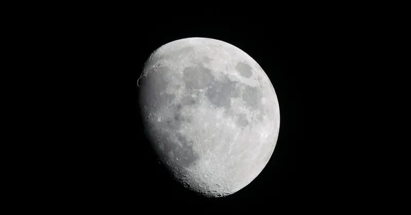 Close-up photograph of the moon against a dark night sky, showcasing its craters and surface details.