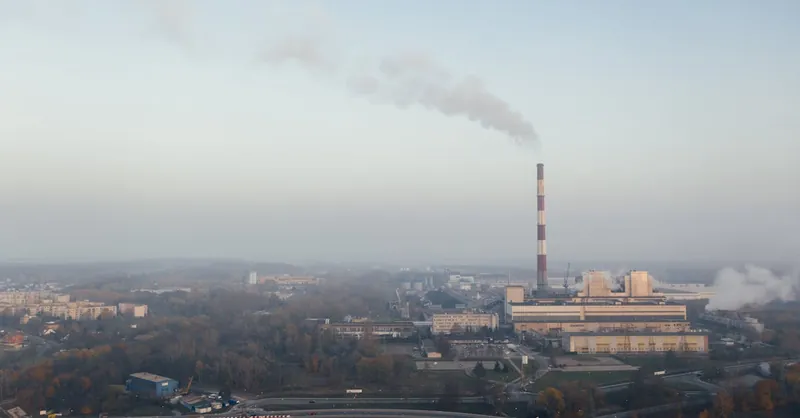 Aerial shot of a power plant emitting smoke, highlighting urban air pollution and industrial impact.