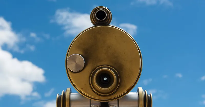 A close-up of a golden telescope against a clear blue sky, perfect for celestial observation.