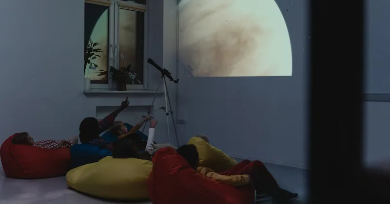 A group of kids learning astronomy with a telescope and projected planet image indoors.