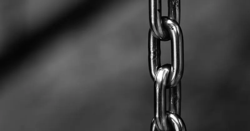 Detailed close-up of a strong shiny metallic chain link against a blurred background, emphasizing security.