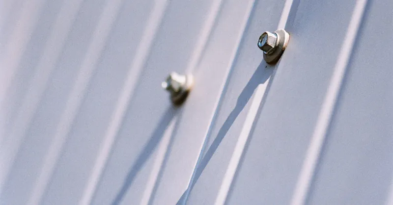 Detailed view of metal screws securing a steel sheet, highlighting durability.