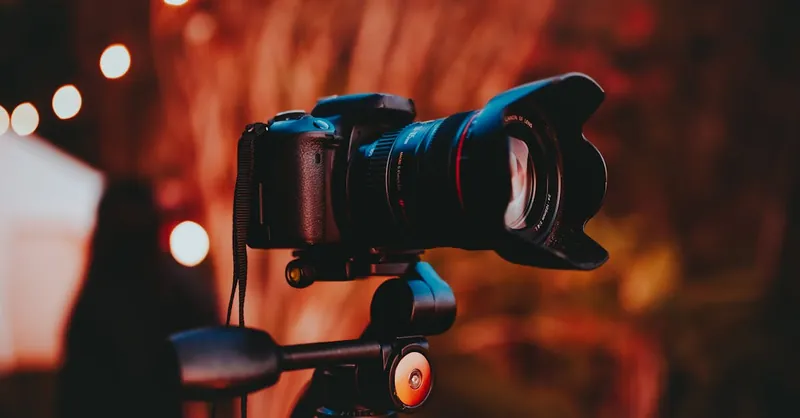 Close-up of a professional camera mounted on a tripod with warm lighting, perfect for capturing outdoor scenes.