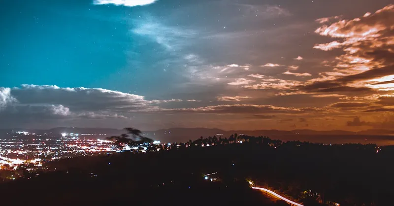 A breathtaking view of a cityscape at twilight showcasing vibrant light trails and a dramatic sky.
